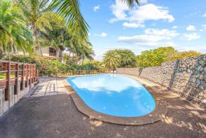 リヴィエール・ノワールにあるNumi Bay - Amazing Apartment with Morne Viewの石壁の隣にある青い大型スイミングプール