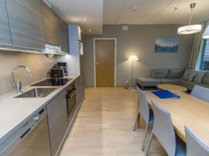 Una cocina y una sala de estar con una mesa y un sofá. en Holiday Home Ruka ski chalets ii huoneisto 2605 by Interhome, en Rukatunturi 