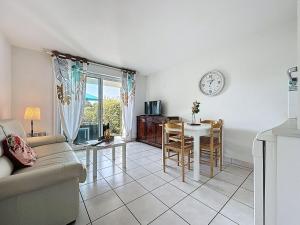 ein Wohnzimmer mit einem Tisch und einer Uhr an der Wand in der Unterkunft Apartment L'Orée du Golf-3 by Interhome in Pornic