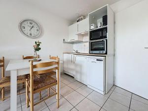 eine Küche mit einem Tisch und einer Uhr an der Wand in der Unterkunft Apartment L'Orée du Golf-3 by Interhome in Pornic