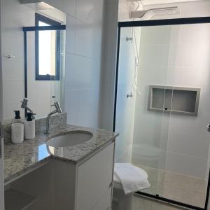 バウルにあるApartamento Amplo com Vista em Bauruの洗面台とシャワー付きの白いバスルーム
