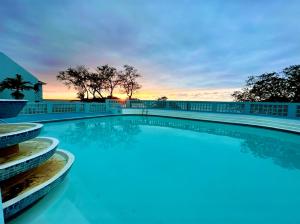 a swimming pool with a sunset in the background at Gorgeous 1 Bedroom Gem at 7 Miles Beach Negril Point Village in Negril Aerodrome