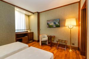 a hotel room with a bed and a chair and a table at Grand Hotel Duca D'Este in Tivoli Terme