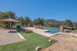 a swimming pool with chairs and an umbrella at Finca Las Cabrillas La Nava in La Nava