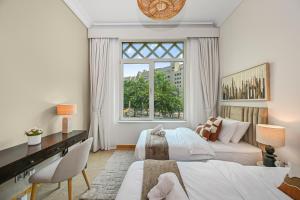 迪拜The Palm Jumeirah Shoreline Living l 3BR Elegant Resort Style Entire Home l Beach Access的一间卧室，有两张床、一张书桌和一扇窗户 更多81张照片