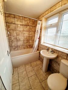 een badkamer met een bad, een toilet en een wastafel bij 4 Bedroom Rayleigh Town House in Rayleigh