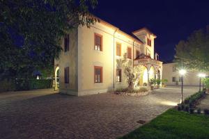 Villa dei Tigli 920 Liberty Resort في Rodigo: مبنى أبيض كبير مع فناء في الليل