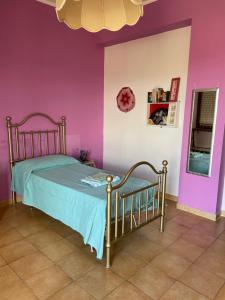 Un dormitorio con una cama y una pared morada. en Appartamento Hipponion, en Vibo Valentia 3 fotos más