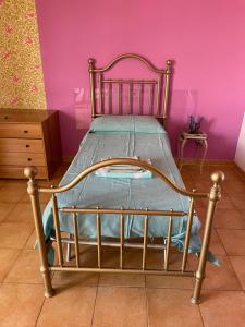 Cama pequeña en habitación con pared de color rosa en Appartamento Hipponion, en Vibo Valentia