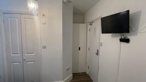 a hallway with a tv on the wall and a door at Papa guest in Poole