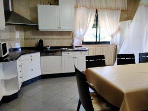 eine Küche mit weißen Schränken und einem Tisch mit Stühlen in der Unterkunft Chalet con piscina in Tabagón