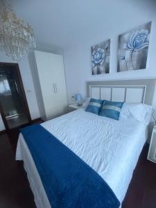 a bedroom with a large bed with blue pillows at Casa Parlera in Ribeira