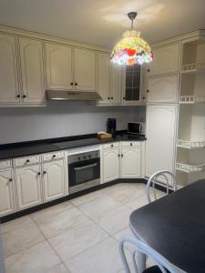 a kitchen with white cabinets and a chandelier at Casa Parlera in Ribeira