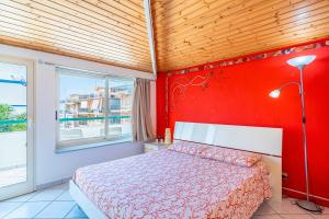 a bedroom with a red wall with a bed and a window at Da Merygiò in Marina di Ragusa