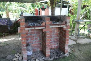 an outdoor brick oven in a yard with a bottle at Capital O 91186 Rumah Rehat Bukit Inas 