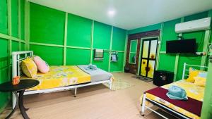 a green room with two beds and a television at Capital O 91187 D'dusun Raudhah Chalet in Baling