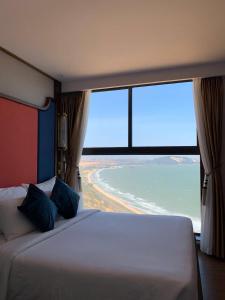 ムイネーにあるHala Beachfront Condotel Mui Neの大きな窓のある部屋にある大きなベッド
