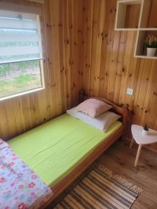 a small bed in a wooden room with a window at domek holenderski in Mieroszyno