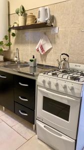 una cucina con una stufa bianca e un lavello di Aloha Teo - Departamento por Día en Trelew, espacioso y cerca de todo! a Trelew Altre 41 foto