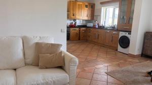 a living room with a white couch and a kitchen at Golden Triangle Retreat Near Quinta do Lago in Almancil
