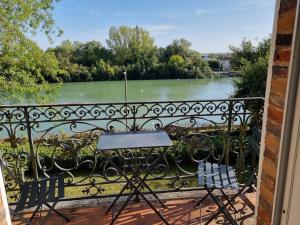 a table and chairs on a balcony with a view of a river at Merlin Cottage in Montereau-Fault-Yonne