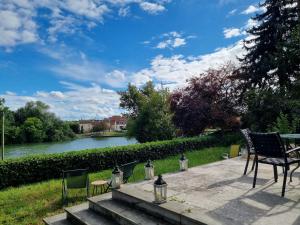a patio with a table and chairs next to a river at Merlin Cottage in Montereau-Fault-Yonne
