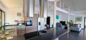 a kitchen with a counter top and a living room at Villa Rêve Austral in Grands Bois