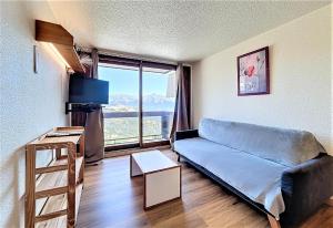 a living room with a couch and a large window at travelski home classic - Résidence Phénix in Le Corbier