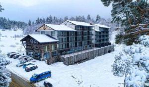 a building in the snow with cars parked in front at Bakuriani Bliss Apartment in Bakuriani