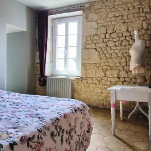 a bedroom with a bed and a table and a window at Gîte de l'épure avec patio in Rémalard en Perche