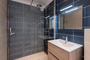 une salle de bain avec un lavabo et une douche avec du carrelage bleu dans l'établissement Canelli - Magnifique Vue Mer, à Pietrosella