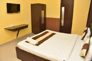 Un dormitorio con una cama con un escritorio y un televisor. en Tipsyy Inn 014, en Gurgaon