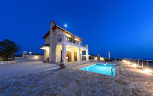 a villa with a swimming pool at night at Orient Villas Volimes in Volímai