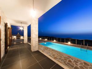 a pool in a house with a blue wall at Orient Villas Volimes in Volímai