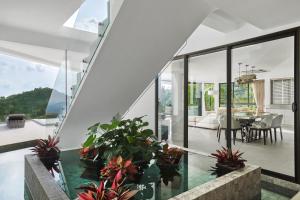 a house with glass walls and potted plants at Icon Villa Samui in Nathon Bay