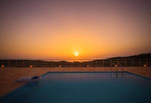 einen Pool mit Sonnenuntergang im Hintergrund in der Unterkunft Orient Villas Volimes in Volímai