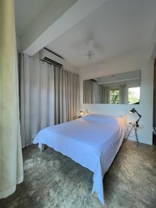 a bedroom with a white bed and a window at Casa - 3 suítes vista para Barra do Sahy in São Sebastião