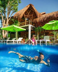 Ein Mann und eine Frau schwimmen im Pool eines Resorts. in der Unterkunft Bamboo Resort Phu Quoc in Phu Quoc