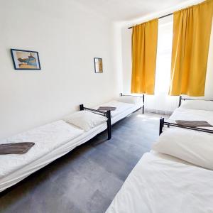 three beds in a room with yellow curtains at Traveller's room F1 u výstaviště in Prague