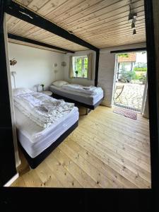 two beds in a room with a wooden floor at Conedue B&B in Væggerløse