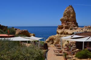 a restaurant with tables and umbrellas next to the ocean at Apartments Miramare Miramonte in Carvoeiro