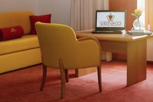 ein Laptop auf einem Tisch mit einem gelben Stuhl in der Unterkunft Hotel Venko in Dobrovo