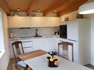 a kitchen with white cabinets and a table and chairs at Schäferhaus in Hemme +18 photos