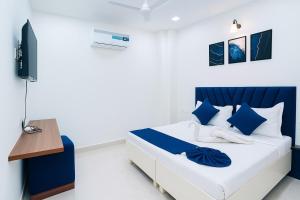 a white and blue bedroom with a bed and a desk at Golden Temple Paradise Stays in Amritsar
