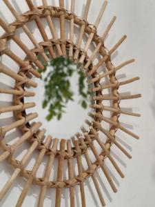 a rattan mirror with a plant in the center at Casa de Pedra in Melide