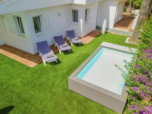 a backyard with a swimming pool and chairs and grass at Villa Calma in Can Picafort +18 photos