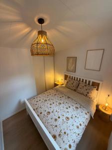 a bedroom with a bed and a light fixture at Casa del Carmen airco, privé hottub en sauna, WiFi and 2 bedrooms in Heinkensand