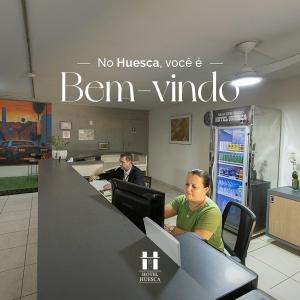 two people sitting at a desk in an office at Hotel Palace Huesca in Presidente Prudente
