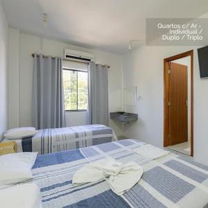 twee bedden in een kamer met een spiegel bij Hotel Palace Huesca in Presidente Prudente