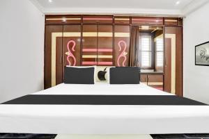 a bedroom with a large white bed with pink handles at Super Hotel O J3 LUXURY ROOMS in Guntūr